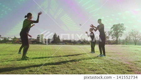 Playing group of four tossing and catching dark object at local park, in sportswear and sneakers Playing group of four tossing and catching dark object at local park, in sportswear and sneakers 141552734