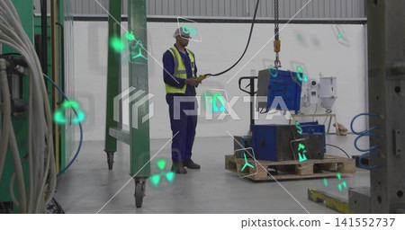 Operating worker in hard hat in shop, controlling hoist with remote lifting blue machine on pallet Operating worker in hard hat in shop, controlling hoist with remote lifting blue machine on pallet 141552737