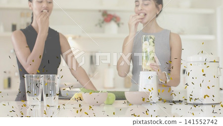 Sampling two women in sleeveless tops tasting blended drink at kitchen island, with blender cup 141552742