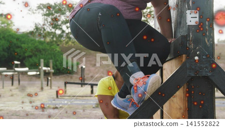 Climbing woman in purple top vaulting wooden obstacle at outdoor park, yellow shirt spotting Climbing woman in purple top vaulting wooden obstacle at outdoor park, yellow shirt spotting 141552822