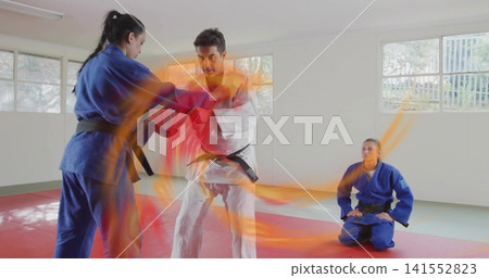 Gripping male instructor and female student practicing throw in bright dojo with gis, black belts Gripping male instructor and female student practicing throw in bright dojo with gis, black belts 141552823