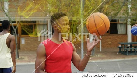 Spinning man in red sleeveless shirt balancing orange basketball at outdoor court, yellow powder Spinning man in red sleeveless shirt balancing orange basketball at outdoor court, yellow powder 141552895