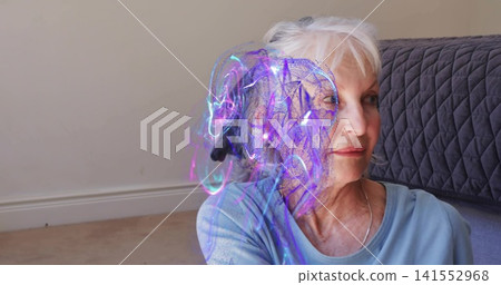 Sitting senior woman wearing light-blue top and thin silver chain at home with hologram, copy space Sitting senior woman wearing light-blue top and thin silver chain at home with hologram, copy space 141552968