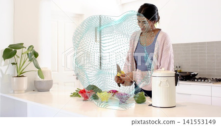 Chopping mid-adult Indian woman in blue tank and cardigan at home kitchen, with knife, vegetables Chopping mid-adult Indian woman in blue tank and cardigan at home kitchen, with knife, vegetables 141553149