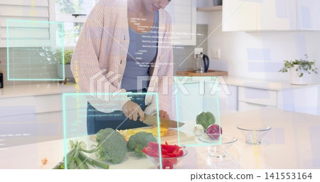 Chopping adult woman in pink cardigan and gray top at glossy kitchen island, holding chef's knife Chopping adult woman in pink cardigan and gray top at glossy kitchen island, holding chef's knife 141553164