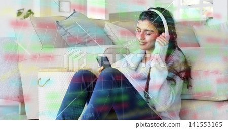 Listening adult woman in sweater on rug at home holding phone touching white headphones, copy space Listening adult woman in sweater on rug at home holding phone touching white headphones, copy space 141553165