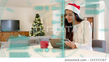 Sitting woman with Santa hat, cream sweater, using tablet, smartphone at home, AR HUD, copy space Sitting woman with Santa hat, cream sweater, using tablet, smartphone at home, AR HUD, copy space 141553167