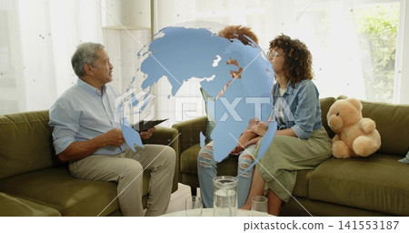 Conducting senior man taking notes on clipboard in living room, wearing blue shirt, globe overlay Conducting senior man taking notes on clipboard in living room, wearing blue shirt, globe overlay 141553187