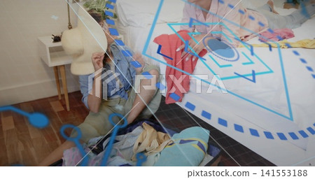 Sorting woman in denim and khaki holding straw hat, organizing clothes by open suitcase in bedroom Sorting woman in denim and khaki holding straw hat, organizing clothes by open suitcase in bedroom 141553188