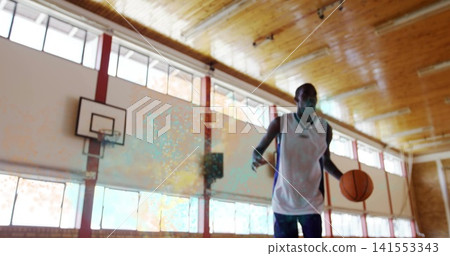 Standing masked man in white sleeveless jersey holding basketball near hoop at gym, copy space Standing masked man in white sleeveless jersey holding basketball near hoop at gym, copy space 141553343