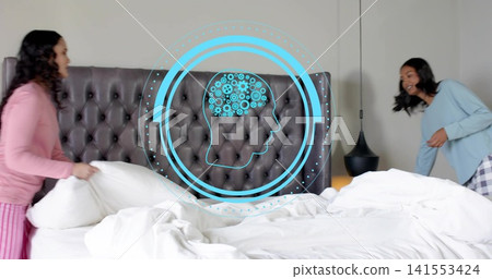 Holding pillow, two women in pajamas adjusting king-size bed in bedroom, with holographic blue head Holding pillow, two women in pajamas adjusting king-size bed in bedroom, with holographic blue head 141553424