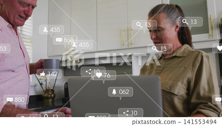 Leaning senior man, woman checking laptop at kitchen counter with gray mug, social overlays, orchid Leaning senior man, woman checking laptop at kitchen counter with gray mug, social overlays, orchid 141553494