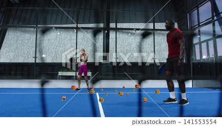 Two players holding rackets in red-and-black-clothes on glass court with emoji balls and net bars Two players holding rackets in red-and-black-clothes on glass court with emoji balls and net bars 141553554