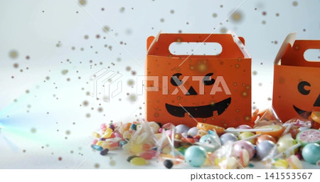 Displaying single orange jack-o-lantern box sitting right of center on white tabletop, with candies Displaying single orange jack-o-lantern box sitting right of center on white tabletop, with candies 141553567