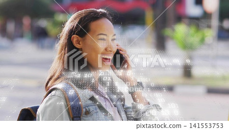 Talking woman holding phone to ear on city sidewalk, wearing denim jacket and backpack with overlay 141553753