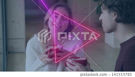 Sipping frothy drinks, couple wearing sweaters sitting in living room with red mugs, neon overlay Sipping frothy drinks, couple wearing sweaters sitting in living room with red mugs, neon overlay 141553785