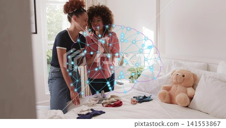 Holding smartphone, two women leaning at bed edge in bedroom, showing neural overlay and teddy bear Holding smartphone, two women leaning at bed edge in bedroom, showing neural overlay and teddy bear 141553867