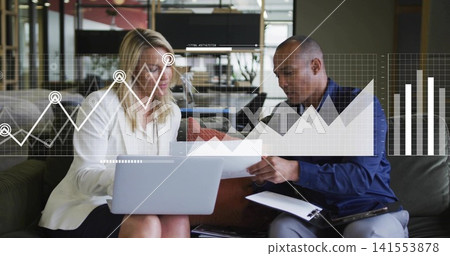 Reviewing papers, white blazer woman and navy shirt man consulting laptop and clipboard in lounge Reviewing papers, white blazer woman and navy shirt man consulting laptop and clipboard in lounge 141553878