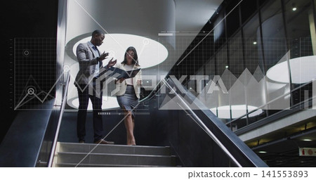 Descending colleagues in business attire holding tablet, cup on stairs by glass wall, data overlay Descending colleagues in business attire holding tablet, cup on stairs by glass wall, data overlay 141553893