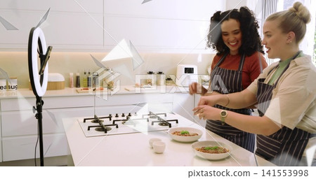 Plating women wearing striped aprons seasoning bowls at kitchen island with ring light, copy space Plating women wearing striped aprons seasoning bowls at kitchen island with ring light, copy space 141553998