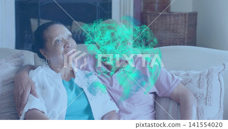 Sitting senior couple cuddling on sofa at home, wearing teal top, pink polo, green digital overlay Sitting senior couple cuddling on sofa at home, wearing teal top, pink polo, green digital overlay 141554020