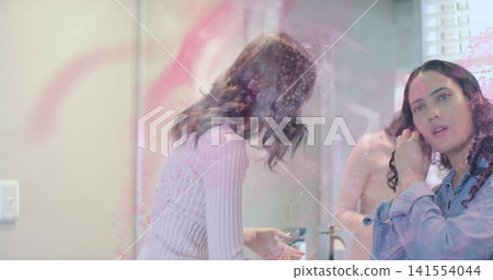 Leaning woman in pink holding soap, woman in blue adjusting hair at bathroom sink, mirror Leaning woman in pink holding soap, woman in blue adjusting hair at bathroom sink, mirror 141554044