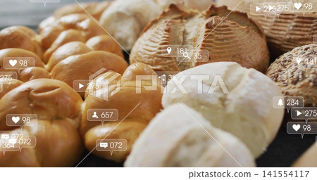 Displaying assortment of golden-brown rolls and scored loaves on bakery counter, with overlay icons 141554117