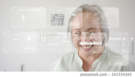 Smiling mature Asian woman wearing pale green blouse viewing HUD panels in small office Smiling mature Asian woman wearing pale green blouse viewing HUD panels in small office 141554165