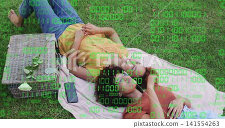Lying two women in colorful-tops on pink blanket in park, with basket, phone, rose, green overlay Lying two women in colorful-tops on pink blanket in park, with basket, phone, rose, green overlay 141554263