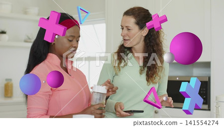 Talking two women in pink jacket, green top with shaker, smartphone at kitchen counter, AR graphics 141554274