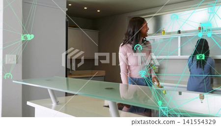 Standing woman in pink ribbed sweater, jeans viewing teal digital overlay in kitchen, glass island Standing woman in pink ribbed sweater, jeans viewing teal digital overlay in kitchen, glass island 141554329