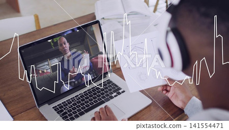 Viewing man wearing headset holding diagrams at home table with laptop waveform overlay, copy space Viewing man wearing headset holding diagrams at home table with laptop waveform overlay, copy space 141554471