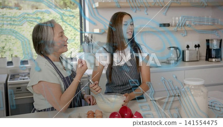 Stirring two females in striped aprons preparing batter in home kitchen with mixing bowl and whisk 141554475