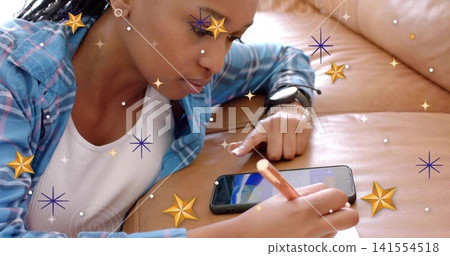 Touching phone with finger, plaid shirt woman holding pencil lounging on tan couch with star filter Touching phone with finger, plaid shirt woman holding pencil lounging on tan couch with star filter 141554518