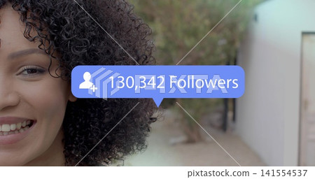 Smiling woman with curly hair facing cam in path, blue bubble showing 130,342 Followers, copy space Smiling woman with curly hair facing cam in path, blue bubble showing 130,342 Followers, copy space 141554537