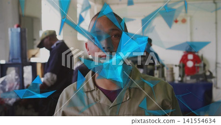 Standing central man wearing beige coverall facing camera in workshop with machines, blue overlay Standing central man wearing beige coverall facing camera in workshop with machines, blue overlay 141554634