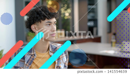 Sitting man wearing plaid over mustard tee with hoop earring at cafe counter, shelves and overlays Sitting man wearing plaid over mustard tee with hoop earring at cafe counter, shelves and overlays 141554639