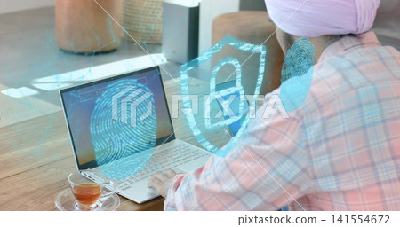 Typing man wearing pink turban plaid shirt at home with laptop fingerprint overlay cup, copy space Typing man wearing pink turban plaid shirt at home with laptop fingerprint overlay cup, copy space 141554672