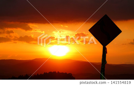 A gentle autumn evening, a slowly setting sun, and a sign silhouetted against the sky. 141554819