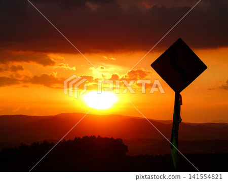 A gentle autumn evening, a slowly setting sun, and a sign silhouetted against the sky. A gentle autumn evening, a slowly setting sun, and a sign silhouetted against the sky. 141554821