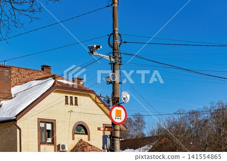 Roadside speed monitoring camera and surveillance tech on a concrete pole. Overseeing urban traffic and safety Roadside speed monitoring camera and surveillance tech on a concrete pole. Overseeing urban traffic and safety 141554865