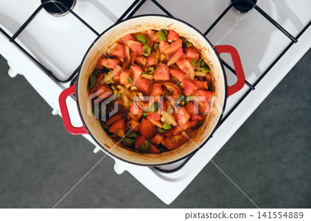 Cooking vegetables in a red pot on a white stove in a kitchen during the day 141554889