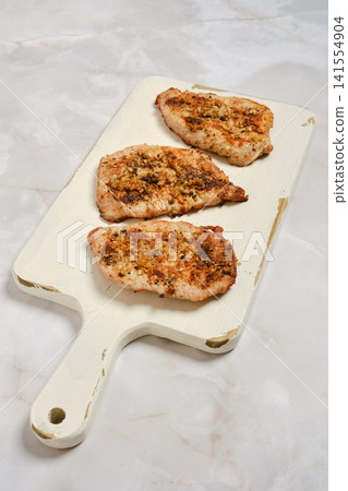 Grilled pork fillets on wooden cutting board with simple presentation Grilled pork fillets on wooden cutting board with simple presentation 141554904