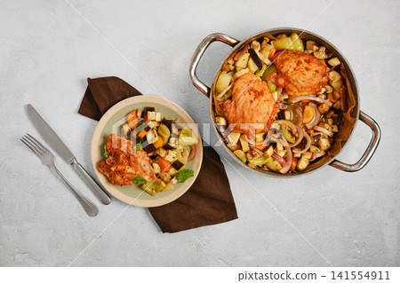 Cooking chicken and vegetables in pots on table Cooking chicken and vegetables in pots on table 141554911