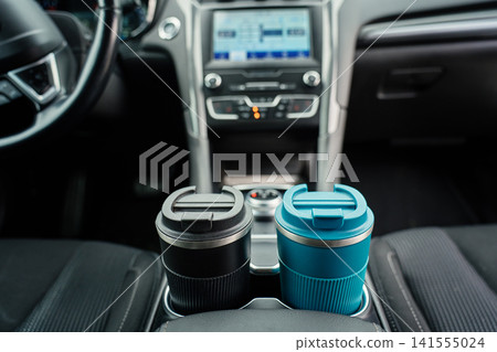 Two reusable coffee cups in car cup holders. Two reusable coffee cups in car cup holders. 141555024