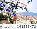 Traditional Turkish Nazar amulets, known as evil eye charms, hang in abundance from the branches of a wishing tree against the scenic backdrop of Pigeon Valley in Cappadocia, Anatolia, Turkey 141555472