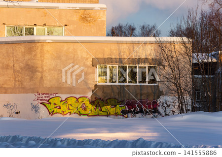Gritty urban wall with vibrant graffiti brightened by golden winter sunlight over deep snowdrifts: Russia - January 13, 2026 Gritty urban wall with vibrant graffiti brightened by golden winter sunlight over deep snowdrifts: Russia - January 13, 2026 141555886
