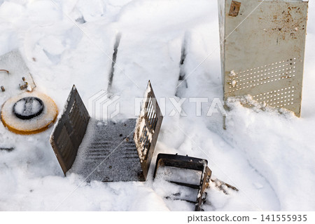Discarded electronic appliance shells and ripped-apart metal junk abandoned in deep winter snow, symbolizing environmental contamination Discarded electronic appliance shells and ripped-apart metal junk abandoned in deep winter snow, symbolizing environmental contamination 141555935