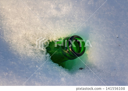 A solitary green bottle, discarded in soft, powdery snow, captures a moment of human indifference toward nature?s quiet winter landscape A solitary green bottle, discarded in soft, powdery snow, captures a moment of human indifference toward nature?s quiet winter landscape 141556108
