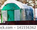 Snow-laden construction trailer, heavily adorned with sharp icicles, stands resilient against the deep freeze. A rustic winter dwelling scene 141556362